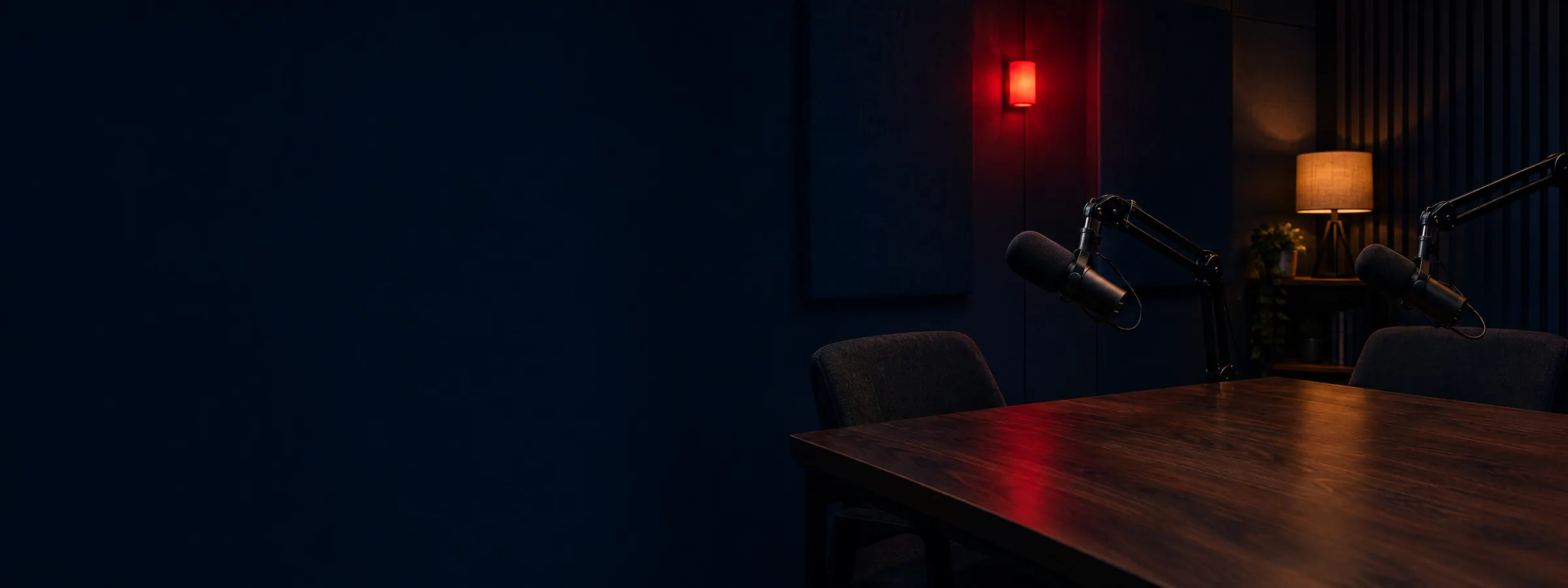 Two studio microphones on a desk in a dark room lit by a red glow